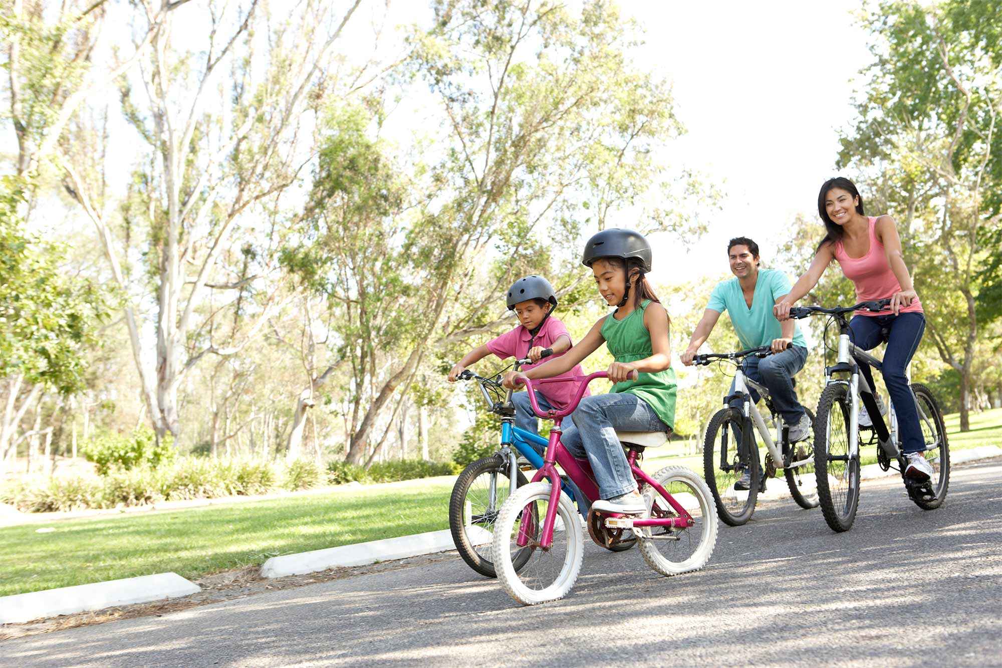 Family riding bikes together in park near Palma Imperial